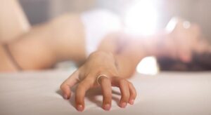 orgasmo femenino, chica agarrada a cama
